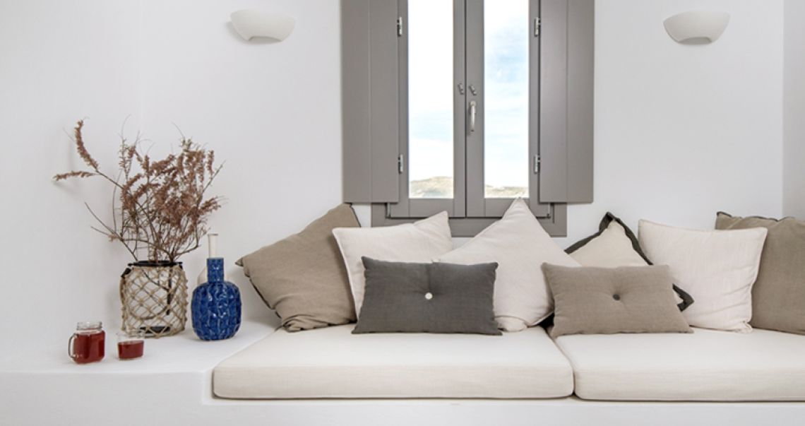 Relaxing window seat corner styled with dried botanicals, a blue textured vase, and glasses of red juice.