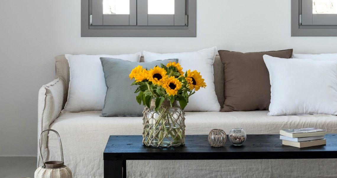Cozy living area featuring a beige sofa with mixed throw pillows and a black coffee table topped with a vase of fresh sunflowers.