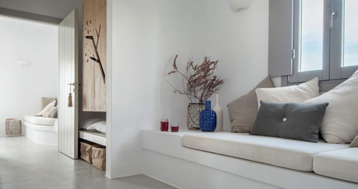 Bright living space featuring a built-in white window seat with mixed grey cushions, a blue vase, and unique wooden wall decor.