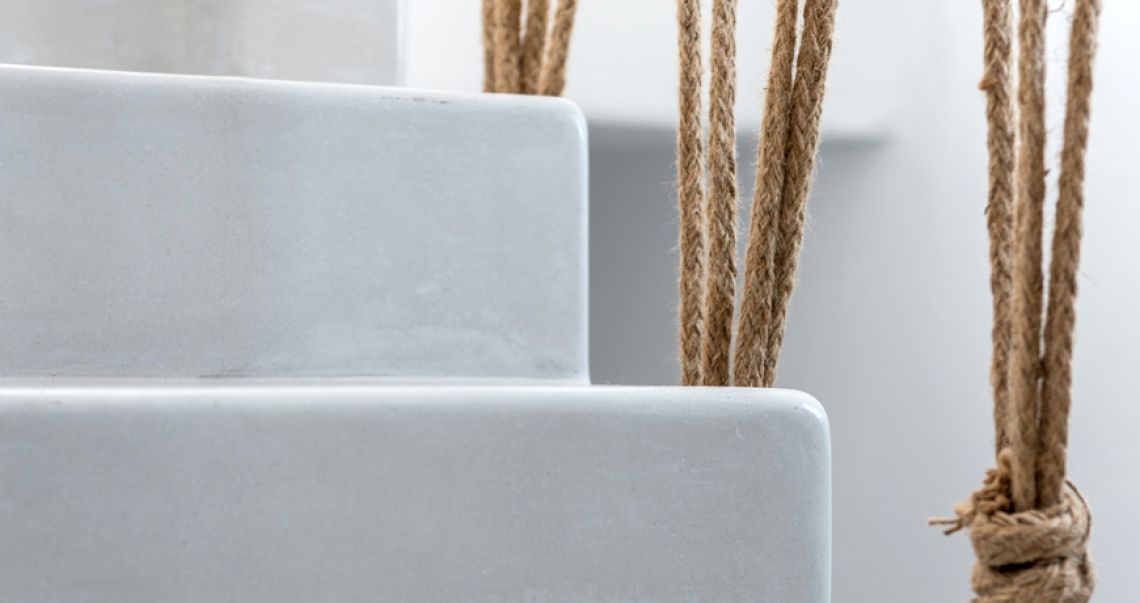 Detail of a smooth white staircase featuring a rustic natural rope railing.